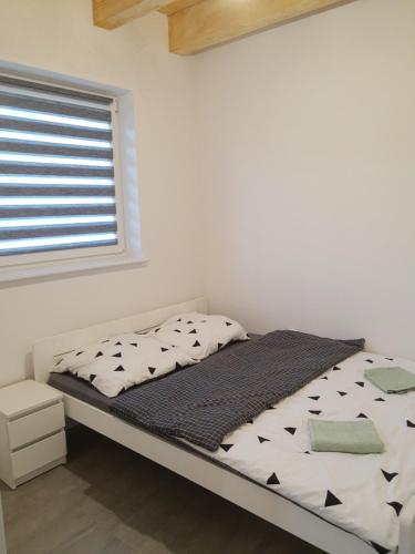 Bett in einem weißen Zimmer mit Fenster in der Unterkunft Domek Bobrowe Zacisze 2 in Karpacz