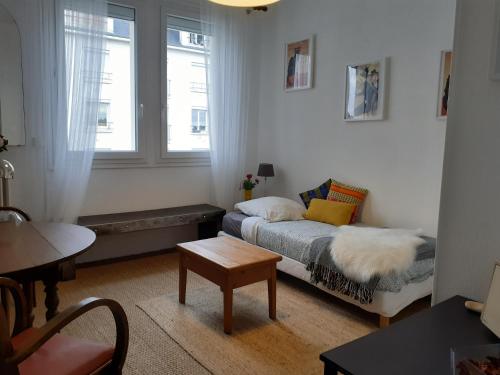 a small living room with a bed and a table at Appartement cosy et lumineux 1 à 3 personnes in Caen