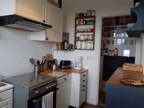 une cuisine avec des armoires blanches et un four à plaques de cuisson dans l'établissement Appartement cosy et lumineux 1 à 3 personnes, à Caen