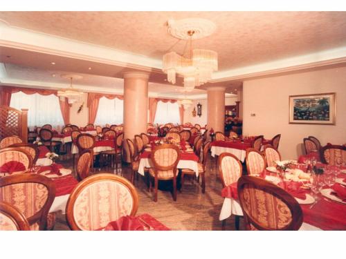 a dining room with tables and chairs and a chandelier at Albergo Gilda in Caldonazzo