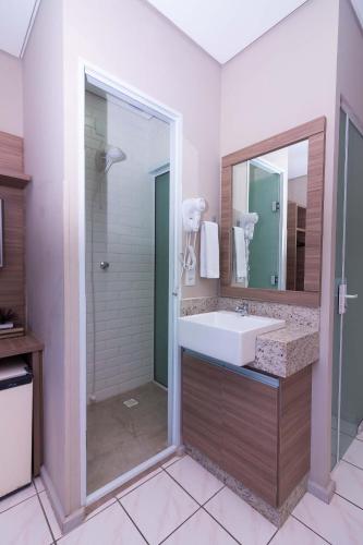 a bathroom with a sink and a mirror at Kennedy Slim Hotel in São José