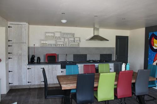 une cuisine avec une table en bois et des chaises colorées dans l'établissement La Belle Vache, à Aumontzey