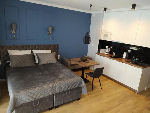 a bedroom with a bed and a table and a kitchen at Apartamenty Wygoda Jurowiecka in Białystok