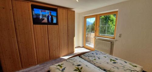 a bedroom with a bed and a tv on a wall at Alpine Lodge Wertach in Wertach