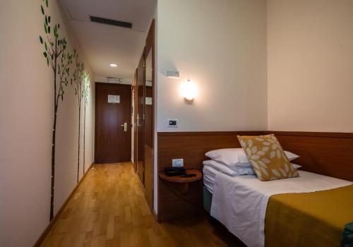 a small room with a bed and a hallway at Hotel Centro Benessere Gardel in Arta Terme