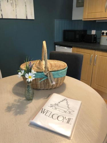 a table with a basket and a welcome sign on it at Fox Cottage in Moffat