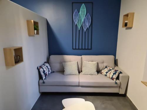 a couch in a living room with a blue wall at Atelier Voyageur in Chartres