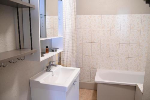 W białej łazience znajduje się umywalka i lustro. w obiekcie Superbe appartement Font Romeu La Pardallera w mieście Font-Romeu-Odeillo-Via