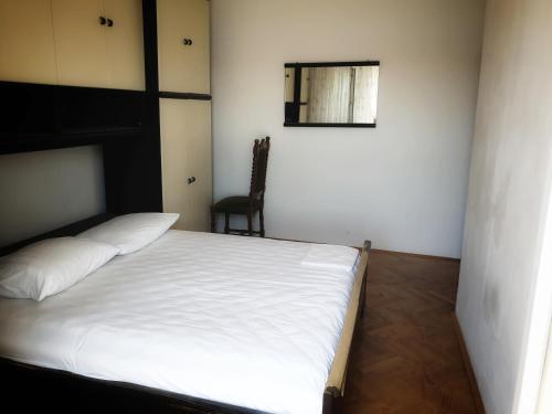 a bedroom with a white bed and a chair at BetaNovalja in Novalja