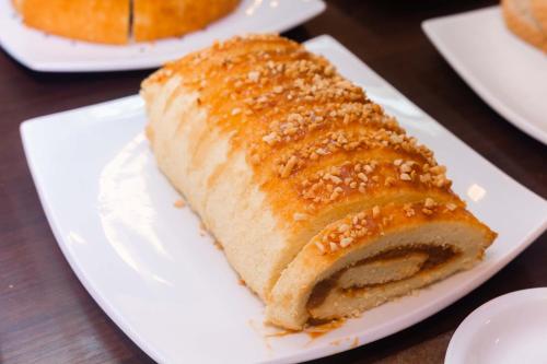 a piece of bread on a white plate on a table at Kennedy Slim Hotel in São José