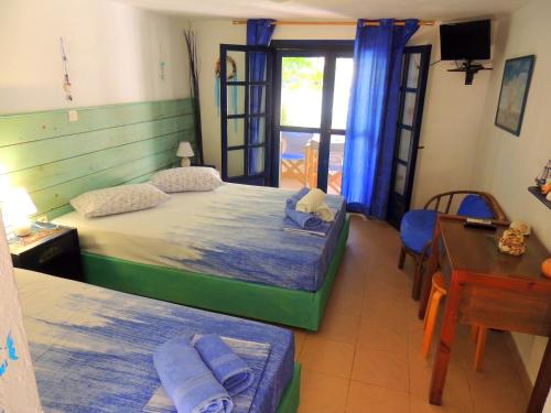 a bedroom with two beds and a table and a desk at Kalamitsi Studios in Kalamitsi