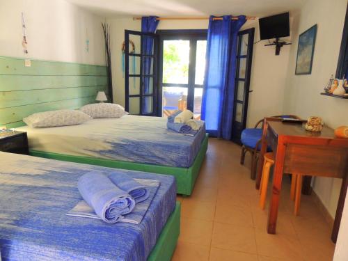 a bedroom with two beds and a desk and a table at Kalamitsi Studios in Kalamitsi
