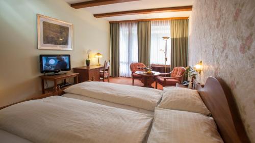 ein Hotelzimmer mit 2 Betten und einem Tisch in der Unterkunft Hotel & Spa Cacciatori in Cademario