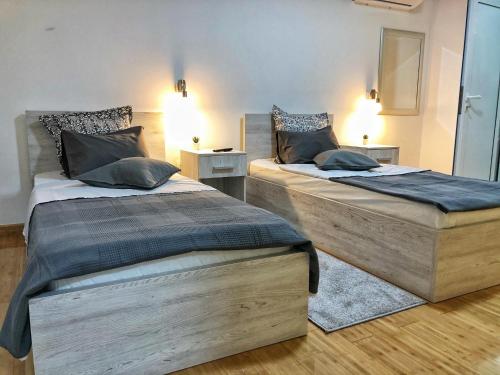 two twin beds in a room with two lamps at TEPIĆ Garni Hotel in Temerin