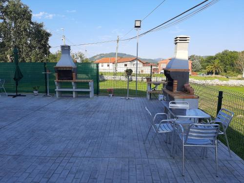 un patio con sillas, mesas y una parrilla en BIULES - LA COLINA, en Arnuero