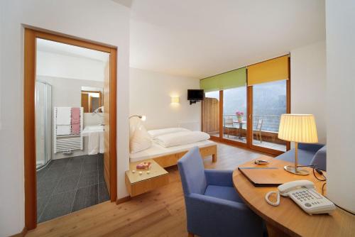 ウルティモにあるVitalhotel Rainerのデスクとベッドルームが備わるホテルルームです。
