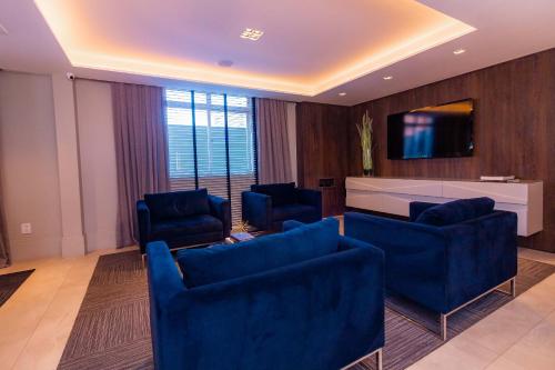ein Wohnzimmer mit blauen Stühlen und einem TV in der Unterkunft Hotel Kennedy in São José