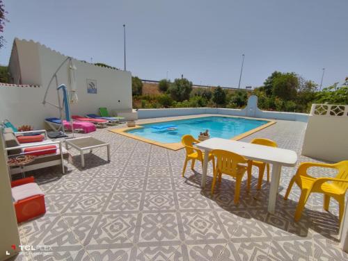 un patio con mesa, sillas y piscina en Vivenda Diniz, en Silves