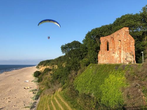a kite flying over a brick building next to a beach at Apartament Nordic in Trzęsacz