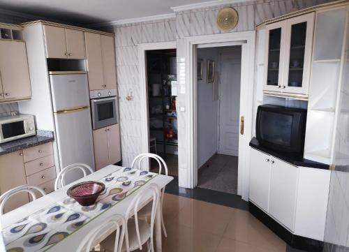 cocina con armarios blancos, mesa y TV en Confortable excelentes vistas en Almería