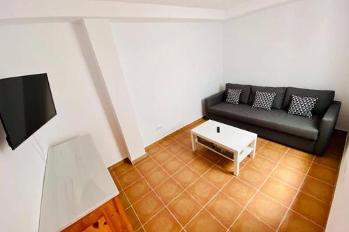 Sala de estar con sofá negro y mesa de centro en Casa Rural Forest Home, en El Bosque