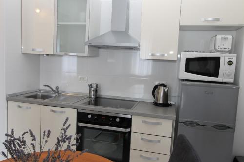 a small kitchen with a microwave and a sink at Apartments Mareblu in Rabac