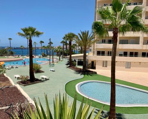 un resort con piscina, palme e un edificio di Los Cristianos Costamar apartment a Los Cristianos