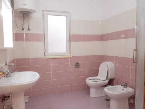 een badkamer met een wastafel, een toilet en een raam bij Guest House Zadeja in Shkodër