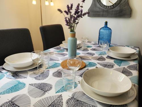 a table with a table cloth with plates and wine glasses at Chez le Petit Peintre in Laboissière-en-Thelle