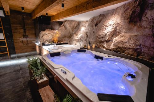 een grote blauwe badkuip in een kamer met een rotswand bij Botun Luxury Apartment in Šibenik