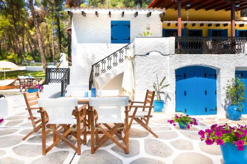 a patio with a table and chairs and a blue door at SANI PINE VILLA in Sani Beach