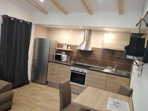 a kitchen with a stainless steel refrigerator and a table at APARTMANI MOROVI DVORI in Drage