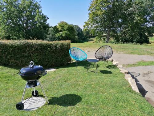 a grill and two chairs sitting in the grass at Gîte de Kerliguit 3 étoiles pour 6 personnes au cœur du Cap-Sizun in Mahalon