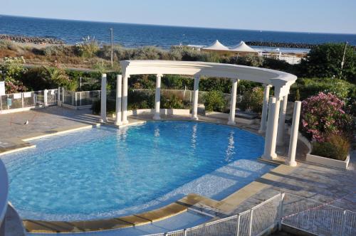 - une piscine avec un kiosque et l'océan dans l'établissement Mandana, au Cap d'Agde