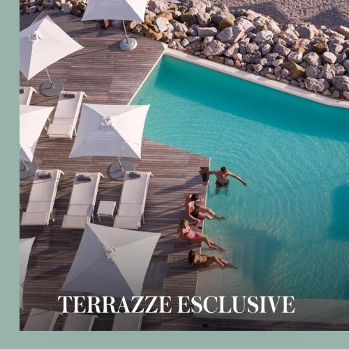 a group of people swimming in a swimming pool with umbrellas at Easy Life in Portopiccolo - Posti spiaggia inclusi in Sistiana