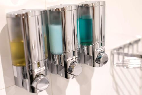 a group of three dispensers with blue liquid in them at Libre Hotel, BW Signature Collection by Best Western in Lima