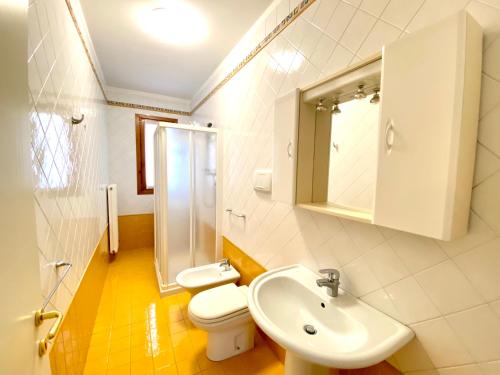 uma casa de banho branca com um lavatório e um WC em Appartamenti Valle Dolce Carraro Immobiliare - Family Apartments em Cavallino-Treporti
