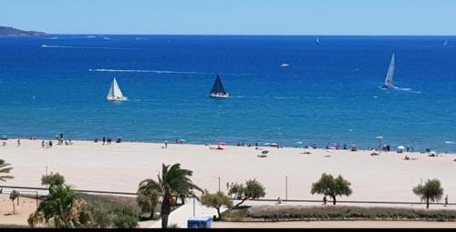 a beach with people and sailboats in the water at Ampuries Delta Apartment in Empuriabrava