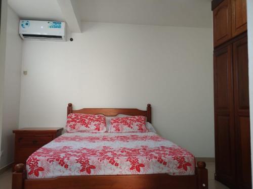 een slaapkamer met een bed met een rood dekbed bij Mandariniers 97232 in Le Lamentin