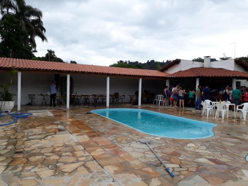 a group of people standing around a swimming pool at Chácara Serra Negra in Serra Negra