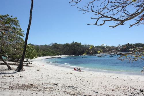 a beach with people sitting on the sand and the water at Cabinas surf Arribadas in Playa Ostional