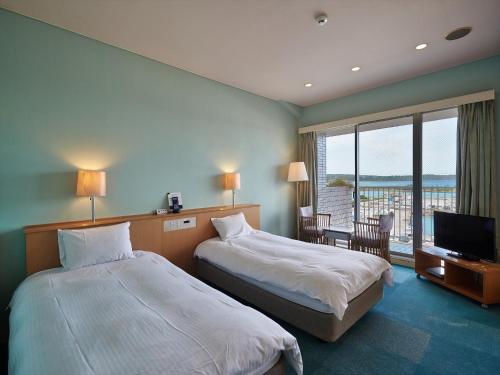 a hotel room with two beds and a flat screen tv at Ocean Resort PMC in Onna
