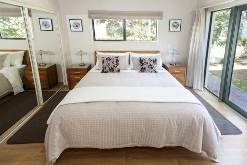 a bedroom with a large white bed and windows at Allegra House in Paihia