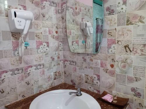 ein Badezimmer mit einem Waschbecken und einem Telefon an der Wand in der Unterkunft เซราะกราว บูติก รีสอร์ท Sohground Boutique Resort in Prakhon Chai
