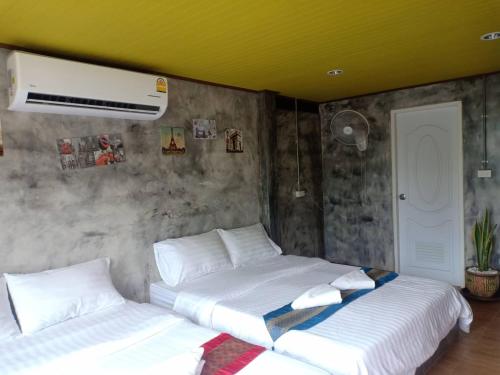Duas camas num quarto com um tecto amarelo em เซราะกราว บูติก รีสอร์ท Sohground Boutique Resort em Prakhon Chai