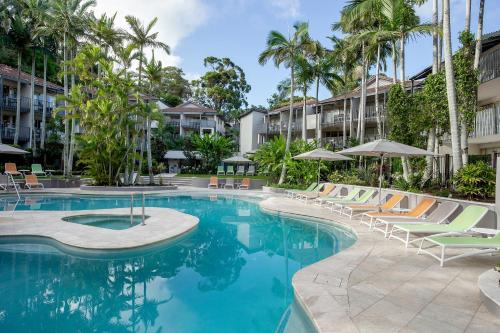 a pool with lounge chairs and umbrellas at a resort at Mantra French Quarter Noosa in Noosa Heads
