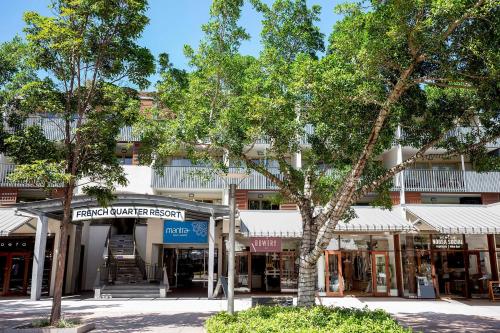 an empty street with trees in front of a building at Mantra French Quarter Noosa in Noosa Heads