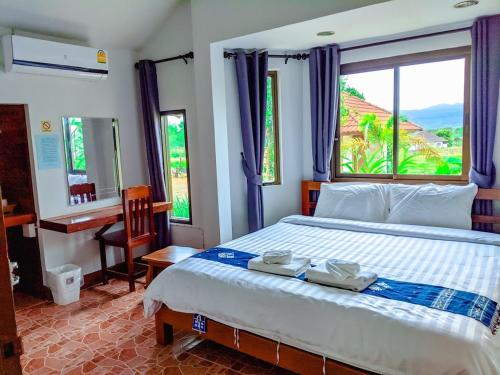 a bedroom with a bed and a desk and a window at วังผา ชาเล่ต์ รีสอร์ท in Ban Fai Mun