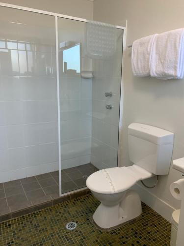 a bathroom with a toilet and a glass shower at In Town Motor Inn in Taree