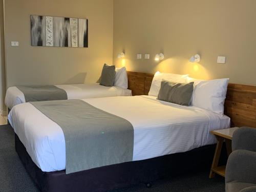 a hotel room with two beds and a chair at In Town Motor Inn in Taree
